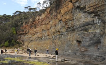 A group of students analysing a rock formation during a field trip