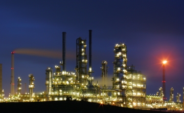 Bright lights of a refinery seen against a dark blue evening sky